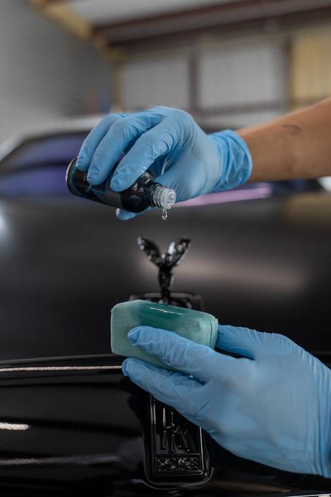 Ceramic coating being dosed onto an applicator over the hood of a Rolls-Royce